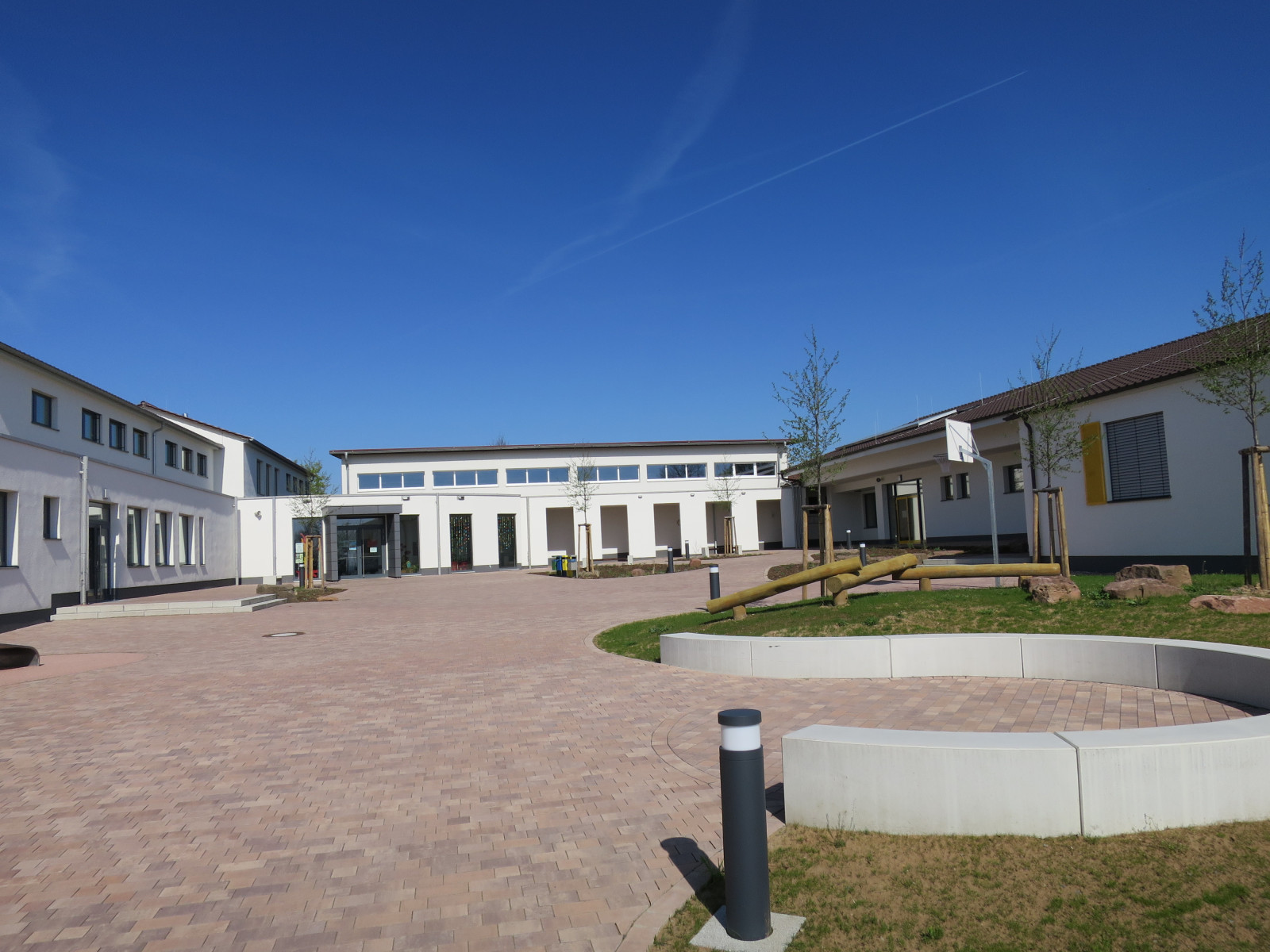 Moderner Gebäudekomplex mit grünem Hof und klar blauem Himmel.