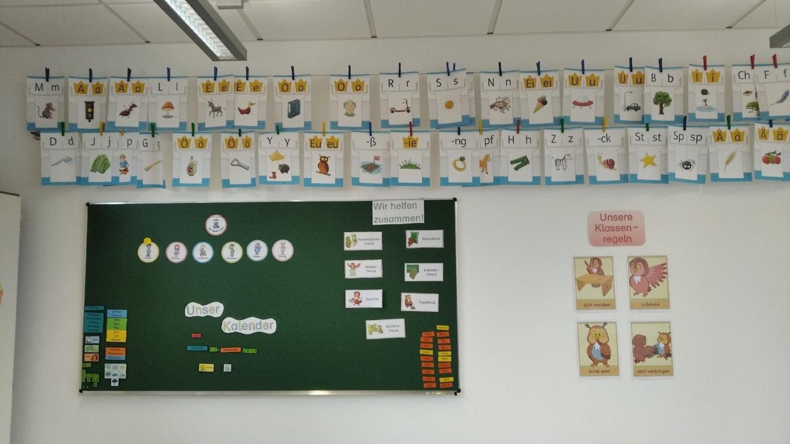 Wand im Klassenzimmer mit Alphabet-Postern und Tafel mit Unterrichtsmaterial.