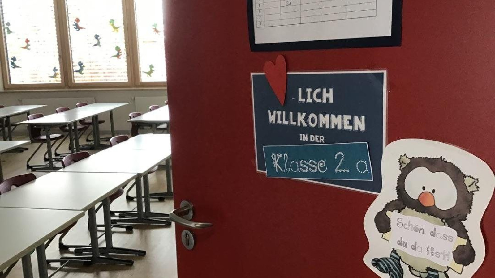 Eingang zu einem Klassenzimmer mit Schildern ‚Willkommen in Klasse 2a‘ und einer Eulenfigur.