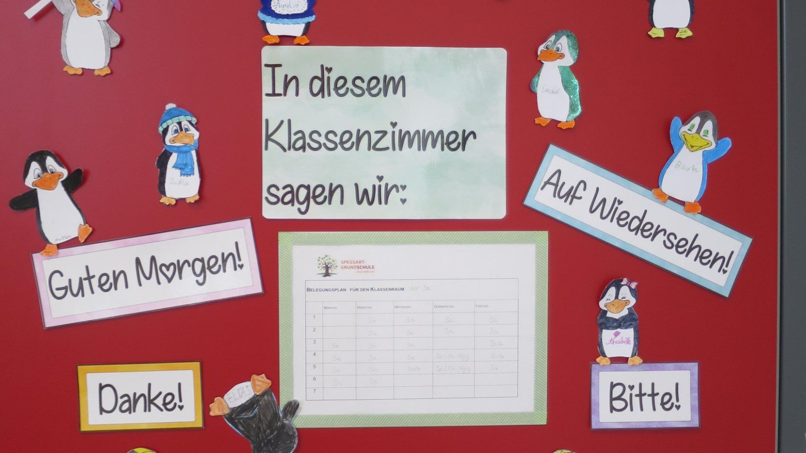 Rote Tür mit Pinguin-Dekorationen und Begrüßungsausdrücken.