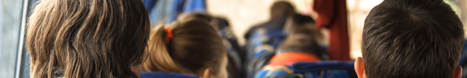 Menschen sitzen in einem fahrenden Bus auf blauen Sitzen.