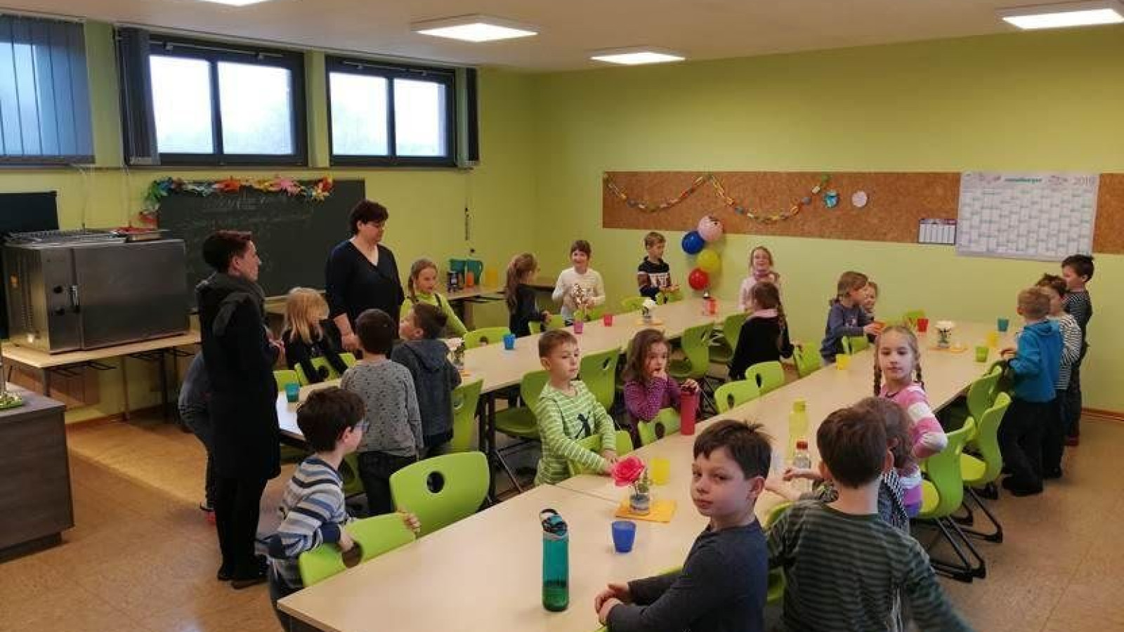 Kinder in einem Klassenzimmer, die an einem Tisch sitzen und miteinander interagieren.