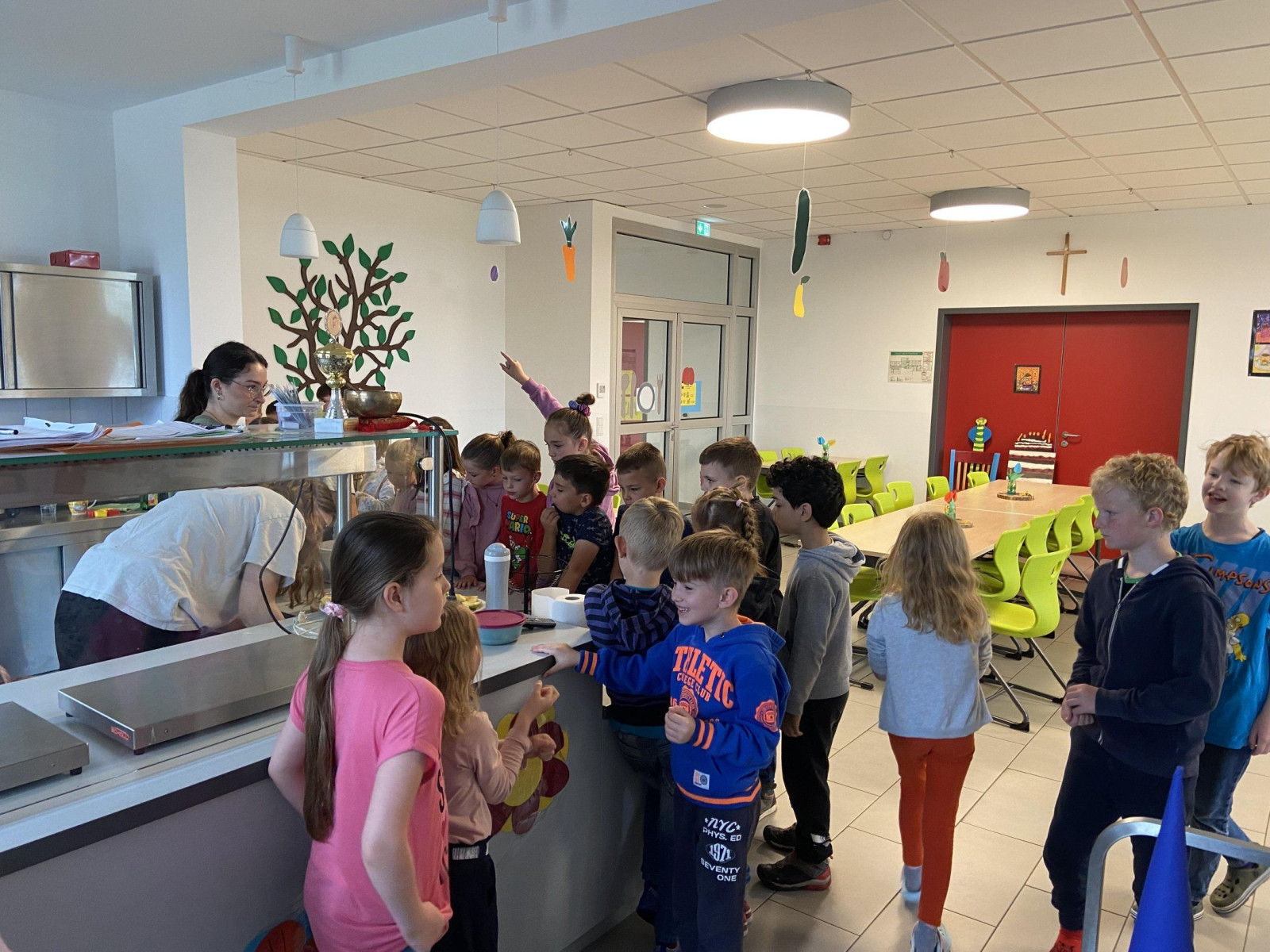 Kinder stehen in einer Schulkantine an der Essensausgabe in einer hellen Umgebung.