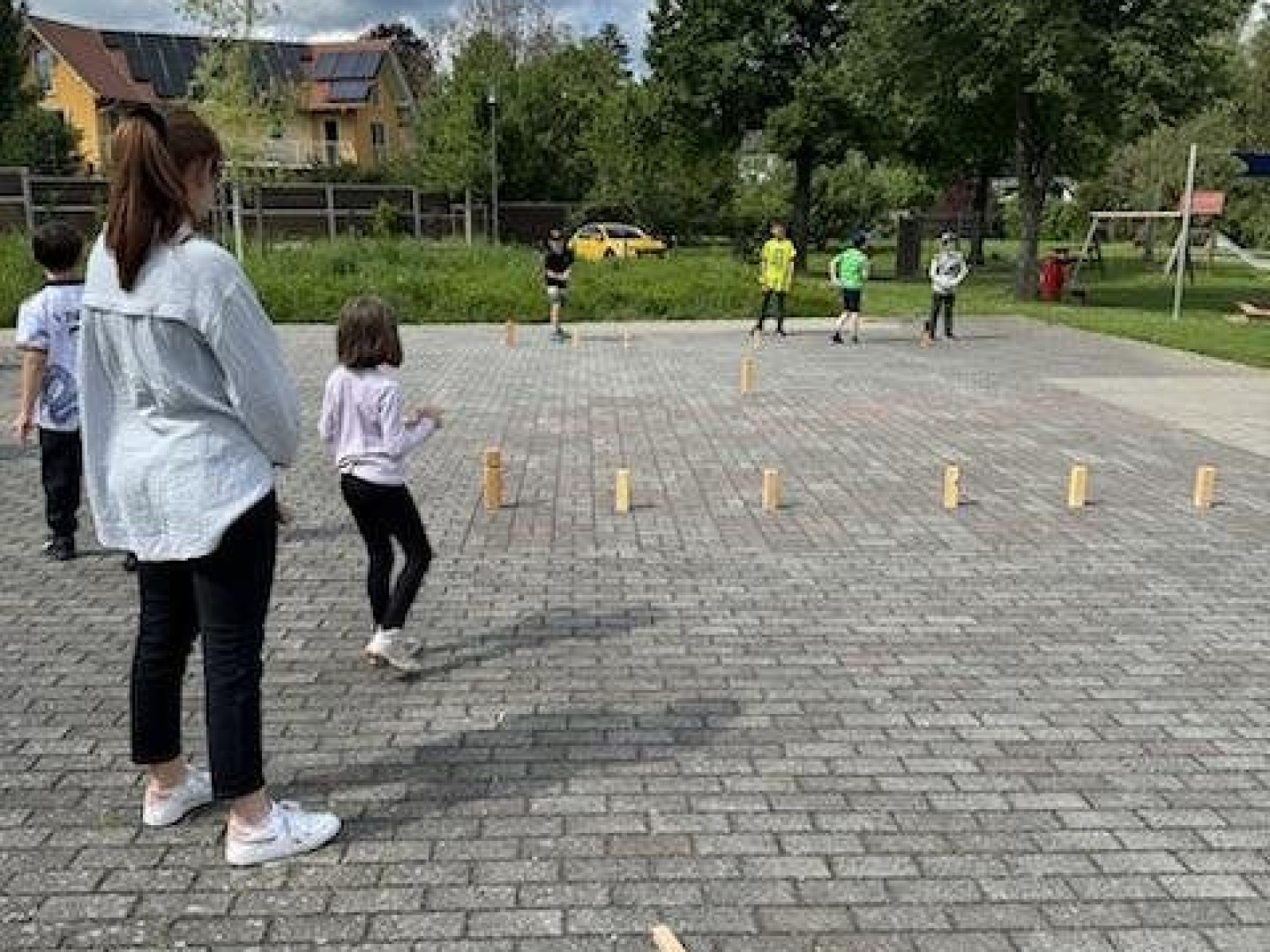 Menschen im Freien auf gepflastertem Boden, die das Spiel Kubb spielen.