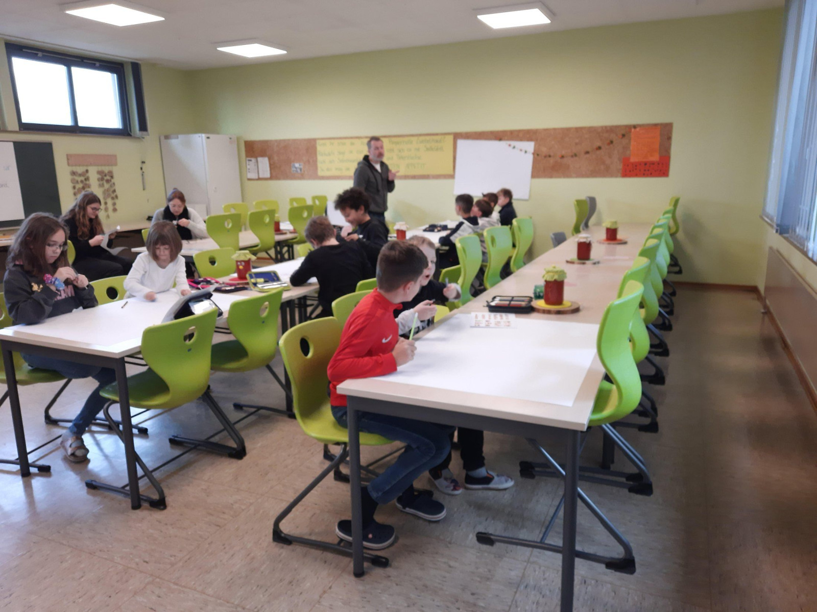Kinder in einem Klassenzimmer an Tischen beim Lernen.