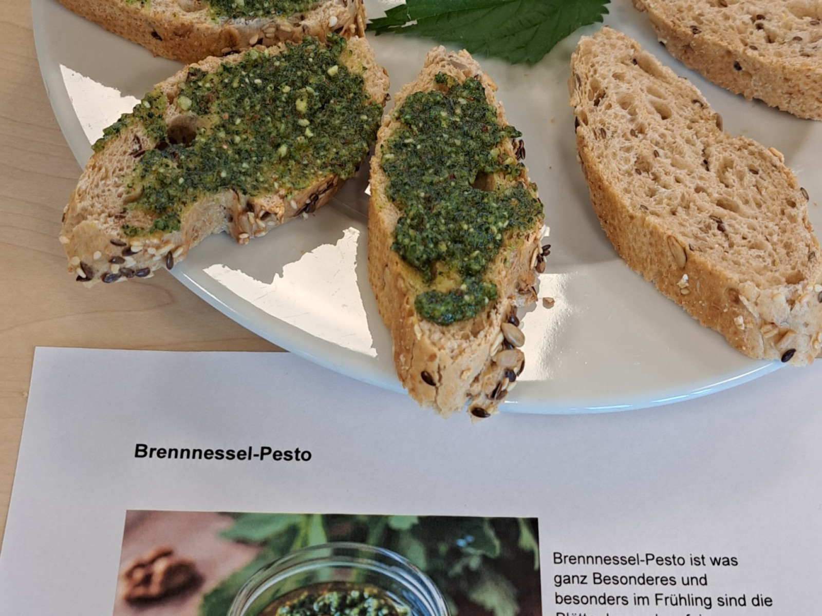 Brotstücke mit Brennnessel-Pesto auf Teller und Text über Brennnessel-Pesto.