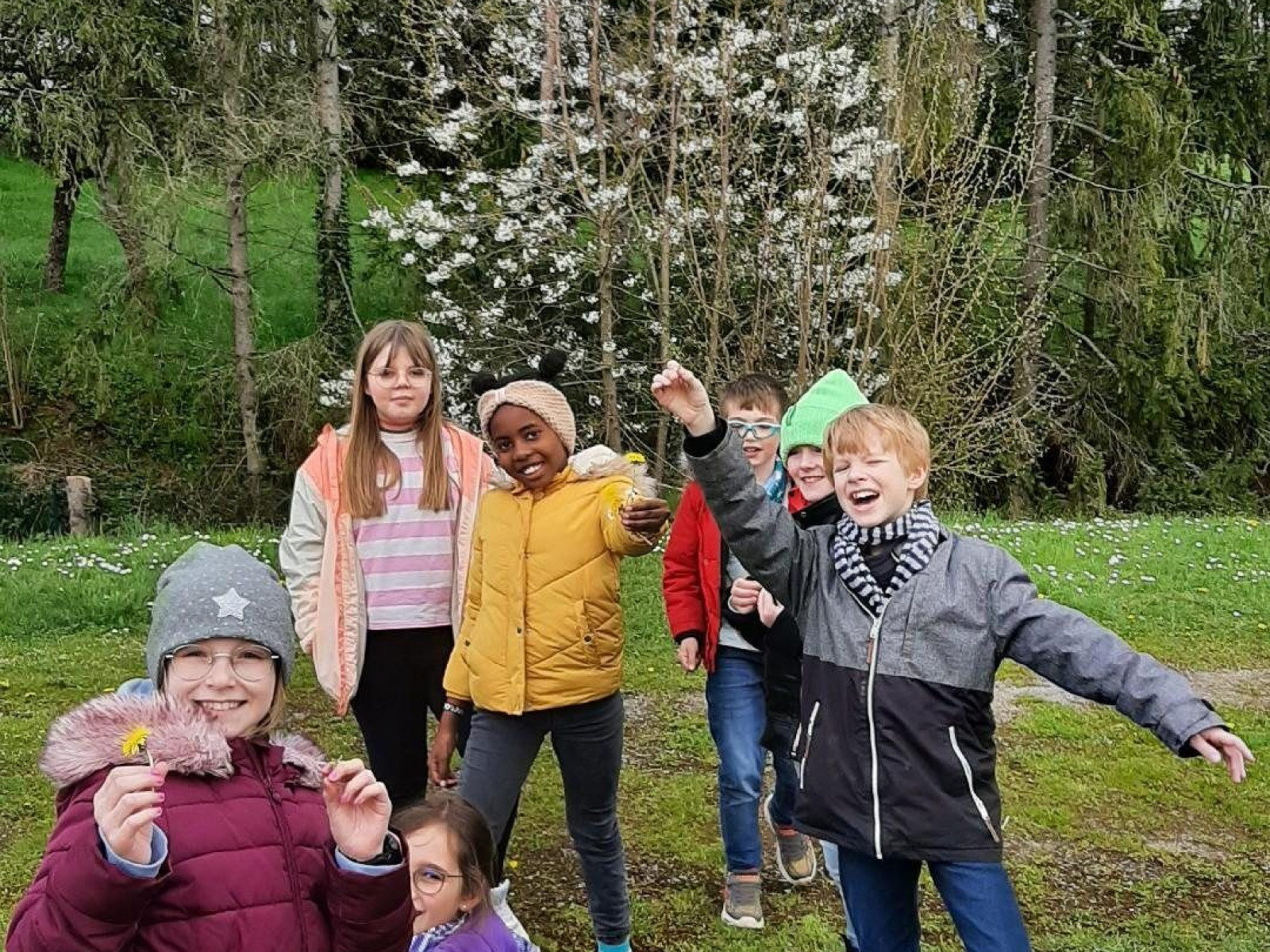 Gruppe von Kindern, die im Park lachen und spielen, mit Bäumen im Hintergrund.